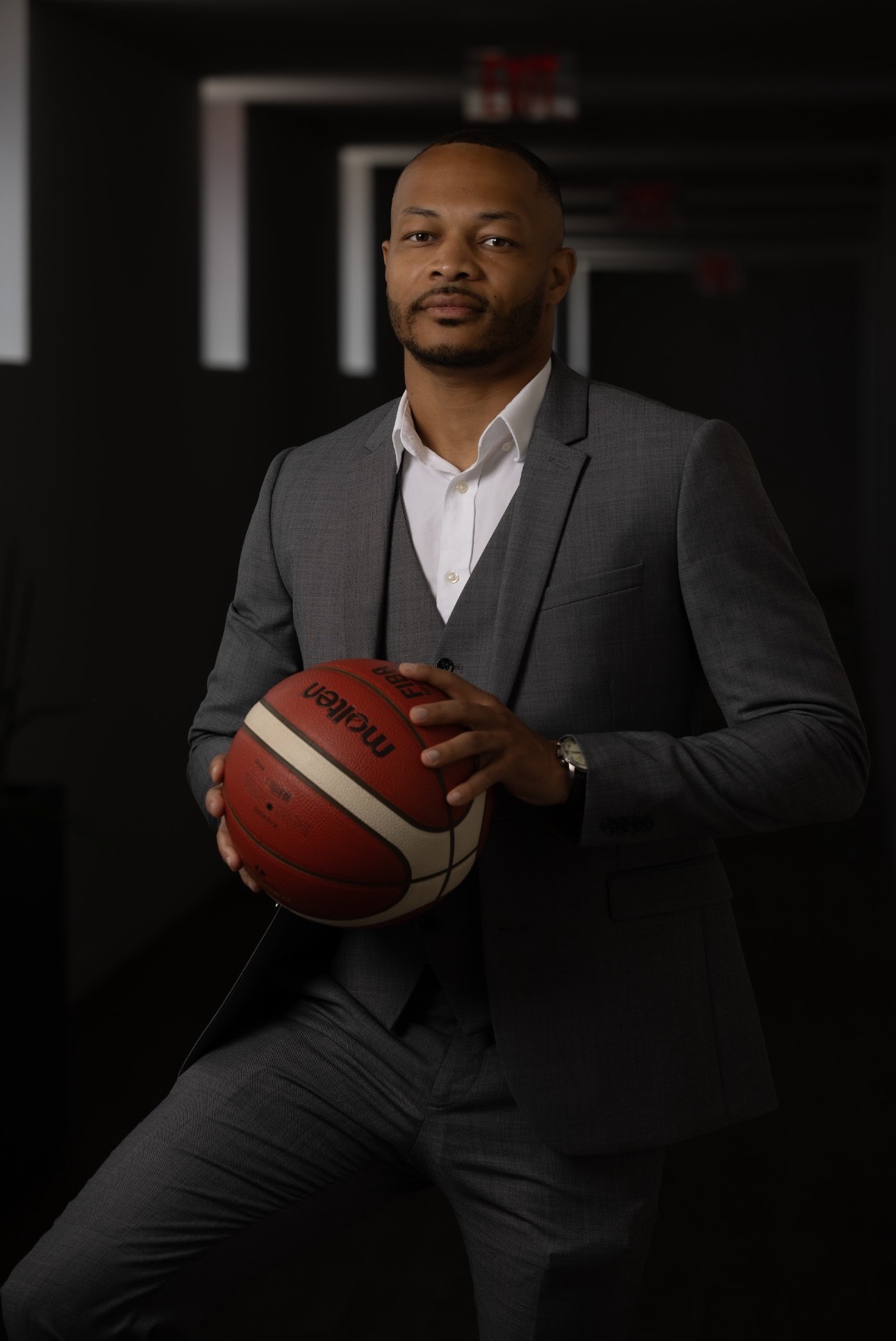Jerry, founder of Dream Lux Retreats, in a grey suit holding a basketball